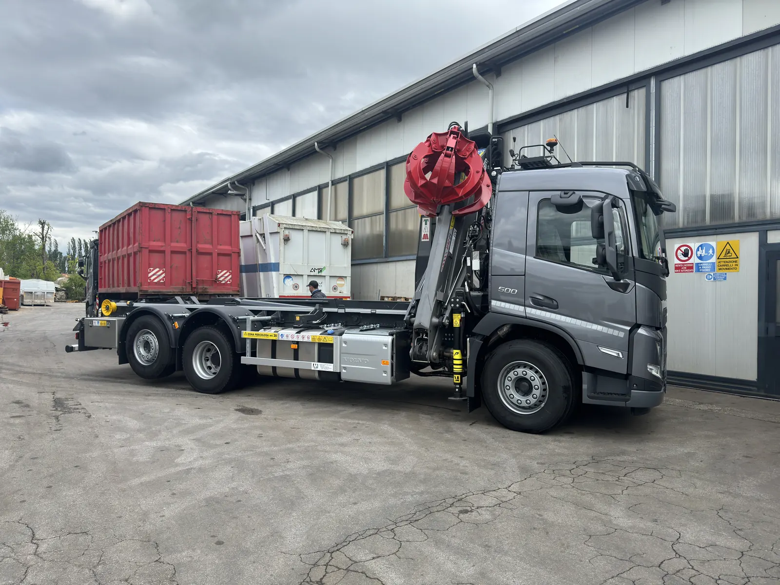 Hooklift truck with crane, and a red skip container